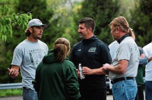 Former Pine-Richland football coach Eric Kasperowicz (center, in black) talks to people during a “Huddle Up for Coach K” rally held in his honor outside of the Pine-Richland School Board’s planning meeting Monday, May 3, 2021. The rally was held to protest the firing of Kasperowicz.