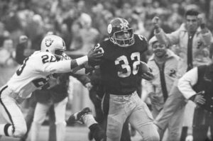In this Dec. 23, 1972, file photo, Pittsburgh Steelers running back Franco Harris (32) eludes a tackle by the Oakland Raiders Jimmy Warren as he runs 42-yards for a touchdown after catching a deflected pass during an AFC Divisional NFL football playoff game in Pittsburgh. Harris scoop of a deflected pass and subsequent run for the winning touchdown, is forever known as the Immaculate Reception.