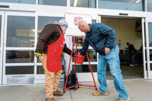Salvation Army bell-ringer Todd Harris tilts the bucket so Matt McIntosh can make a donation Dec. 14 at Greengate Center in Greensburg.