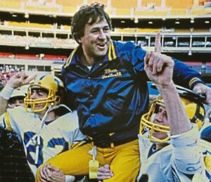 Plum coach Al “Abby” Mauro is carried off the field at Three Rivers Stadium following the Mustangs 10-6 victory over New Castle on Nov. 26, 1983 in the WPIAL Class 4A Division II title game. Two late safeties sealed the win. Mauro died on Nov. 11, 2023.