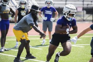 Plum running back coach Deji Karim conducts handoff reps with his players including CJ Hart, front, during practice Aug. 4.