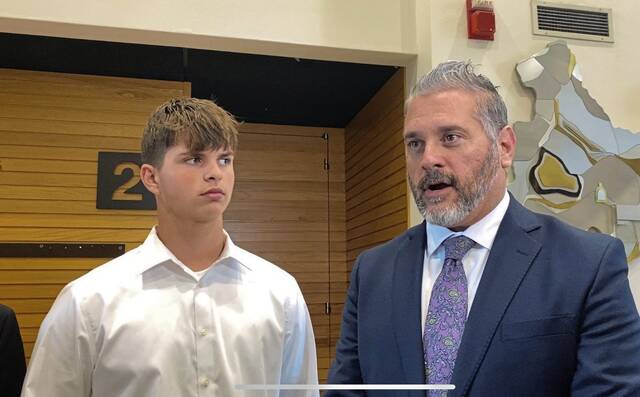 Anthony Smith (left) looks at attorney Steve Toprani while addressing the media on Tuesday at the Westmoreland County courthouse in Greensburg.