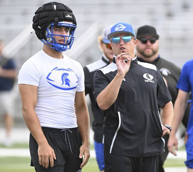 Hempfield coach Nick Keefer speaks with quarterback Dom Detruf during a preseason workout.