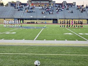 Mt. Lebanon (left) and Norwin girls soccer players stand for the national anthem before Wednesday's game in North Huntingdon.