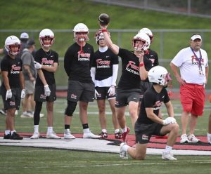 Fox Chapel coach Dave Leasure (left) looks on as quarterback Joey Geller throws against Armstrong during a 7-on-7 game July 9 at Fox Chapel.