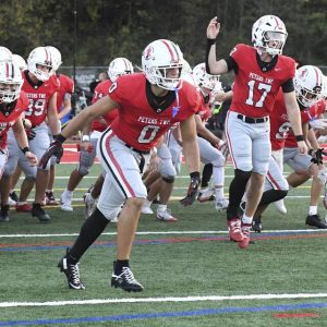 Peters Township’s Lucas Shanafelt (0) and Nolan DiLucia (17) lead the team onto the field before a game against Upper St. Clair last Friday.