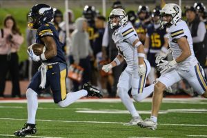 Central Catholic’s Jayden Alexander (left) bursts toward the end zone past Norwin’s Jake Knight (right) and Zack Pawling (center) on Thursday at Carnegie Mellon.
