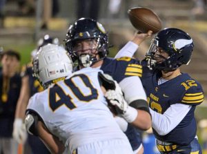 Central Catholic quarterback Owen Herrick (12) throws a pass amidst pressure from Norwin’s Gio Algeiri (40) on Oct. 9 at Carnegie Mellon.
