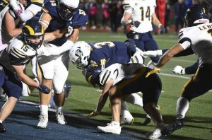 Norwin’s Tristyn Tavares scores a touchdown over Mt. Lebanon’s Sam McAuley on Friday.