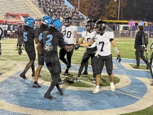 Players from Upper St. Clair and Woodland Hills meet at midfield for the coin toss before their WPIAL Class 5A quarterfinal Friday at the Wolvarena.
