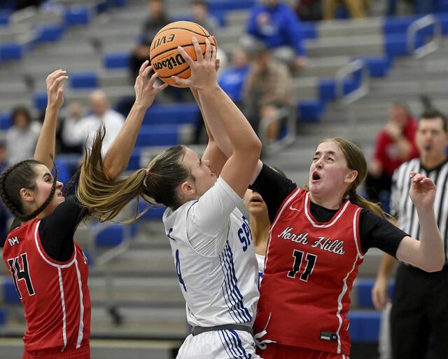 Hempfield’s Lilly Houghtalen grabs a rebound between North Hills’ Sophia Regan (14) and Delaney Amato late in the fourth quarter on Thursday, Dec. 11, 2025, at Hempfield. (Christopher Horner | TribLive)