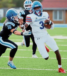Jeannette quarterback Kymon’e Brown looks to evade Leechburg senior Matthew Scitticat on a 11-yard run in September. (Josh Rizzo | For TribLive)