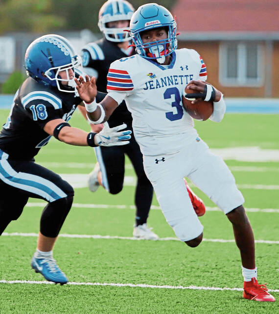 Jeannette quarterback Kymon’e Brown looks to evade Leechburg senior Matthew Scitticat on a 11-yard run in September. (Josh Rizzo | For TribLive)