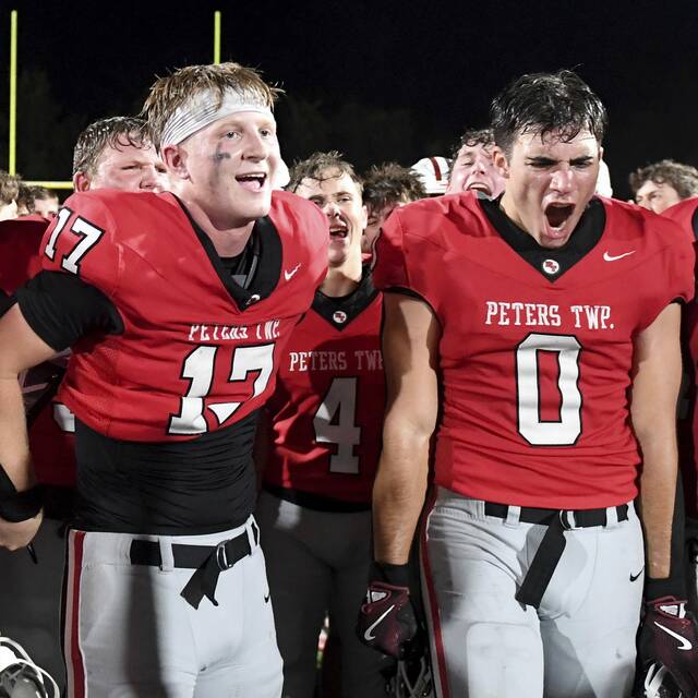 Peters Township quarterback Nolan DiLucia and Lucas Shanafelt celebrate with their team after defeating Upper St. Clair on Sept. 26 at Peters. (Christopher Horner | TribLive)