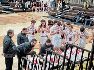 Ligonier Valley coach Dante Porter (kneeling) leads a huddle with his players during the Greensburg Salem Holiday Classic. (Bill Beckner Jr. | TribLive)