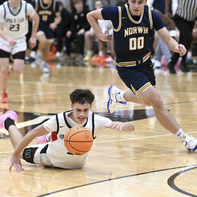 Upper St. Clairs Jake Foster dives for a loose ball under Norwins Nate Kuch on Dec. 9, 2025. (Christopher Horner | TribLive)