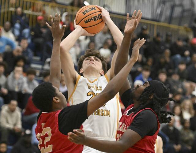 Thomas Jeffersons Nicholas Trklja elevates over Penn Hills Tyrone Johnson and Dallas Smith during WPIAL Class 5A playoff action Friday, Feb. 20, 2026 at Norwin High School. (Chaz Palla | TribLive)