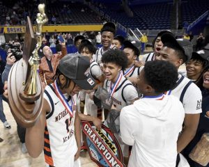 The Neighborhood Academy’s Kedron Gilmore hoists the WPIAL championship trophy with his teammates after defeating Serra Catholic in the Class A final on Thursday, Feb. 26, 2026, at Petersen Events Center. (Christopher Horner | TribLive)