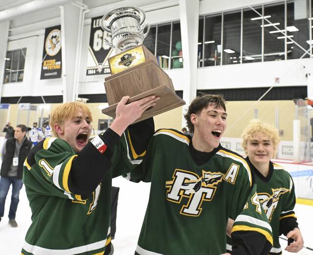 Penn-Traffords Tyler Funk, Jake Lenart and Roman Catello celebrate with the Penguins Cup after beating Hempfield in the PIHL Class 2A championship Monday. (Chaz Palla | TribLive)