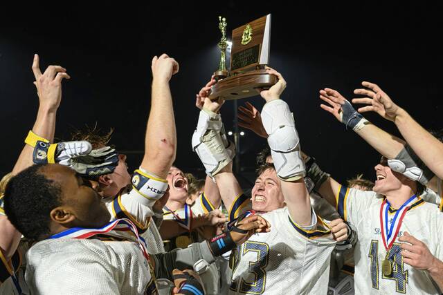 Shady Side Academy's John Poggi (23) hoists the 2026 WPIAL Class 3A championship trophy as he is swarmed by his team after defeating Pine-Richland on Wednesday, May 20, 2026, at Upper St. Clair. (Andrew Palla | For TribLive)