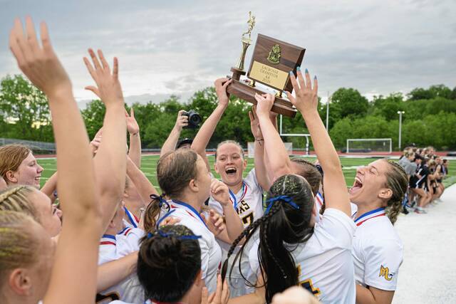 Mars' Anna McGrath (center) hoists the 2026 WPIAL Class 2A girls lacrosse championship trophy following Mars' victory over Quaker Valley in the championship game Thursday, May 21, 2026, at Upper St. Clair. (Andrew Palla | TribLive)